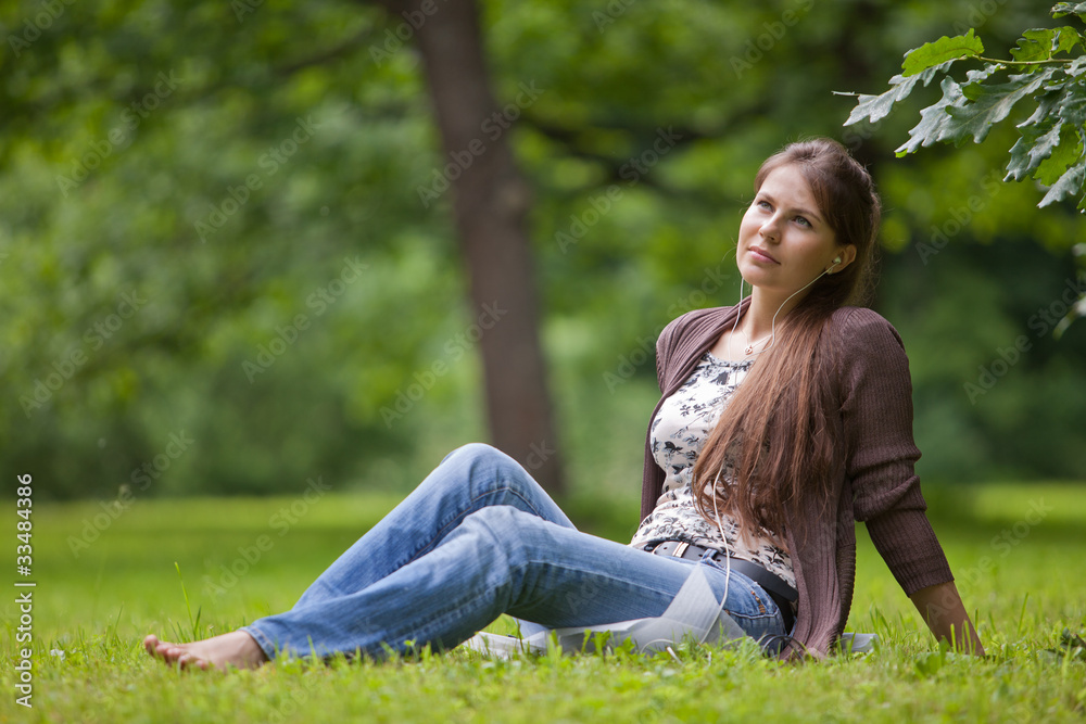 .Young woman with earphones in the park. .Young woman with earphones in the park.