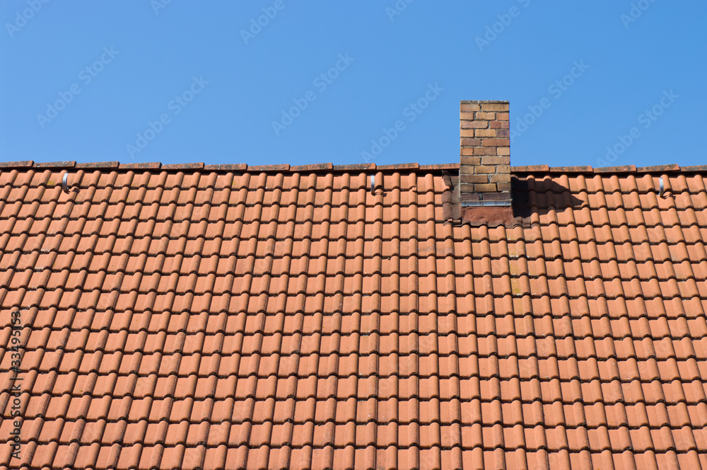 The roof of tiles and chimney against a blue sky. The roof of tiles and chimney against a blue sky.