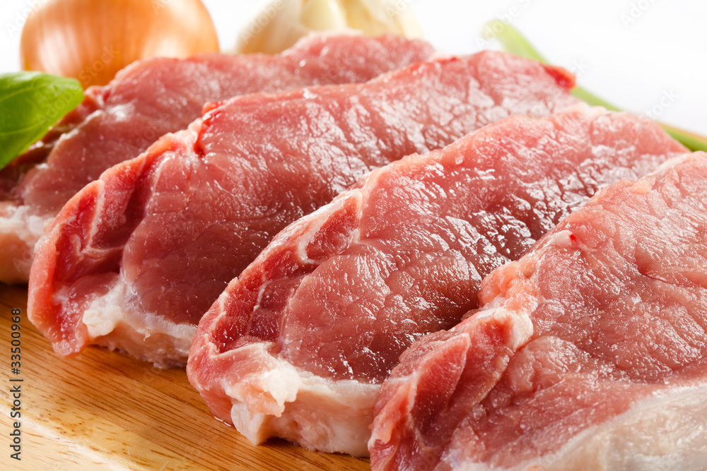 Raw pork on cutting board and vegetables Raw pork on cutting board and vegetables