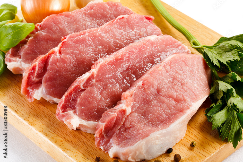 Raw pork on cutting board and vegetables Raw pork on cutting board and vegetables