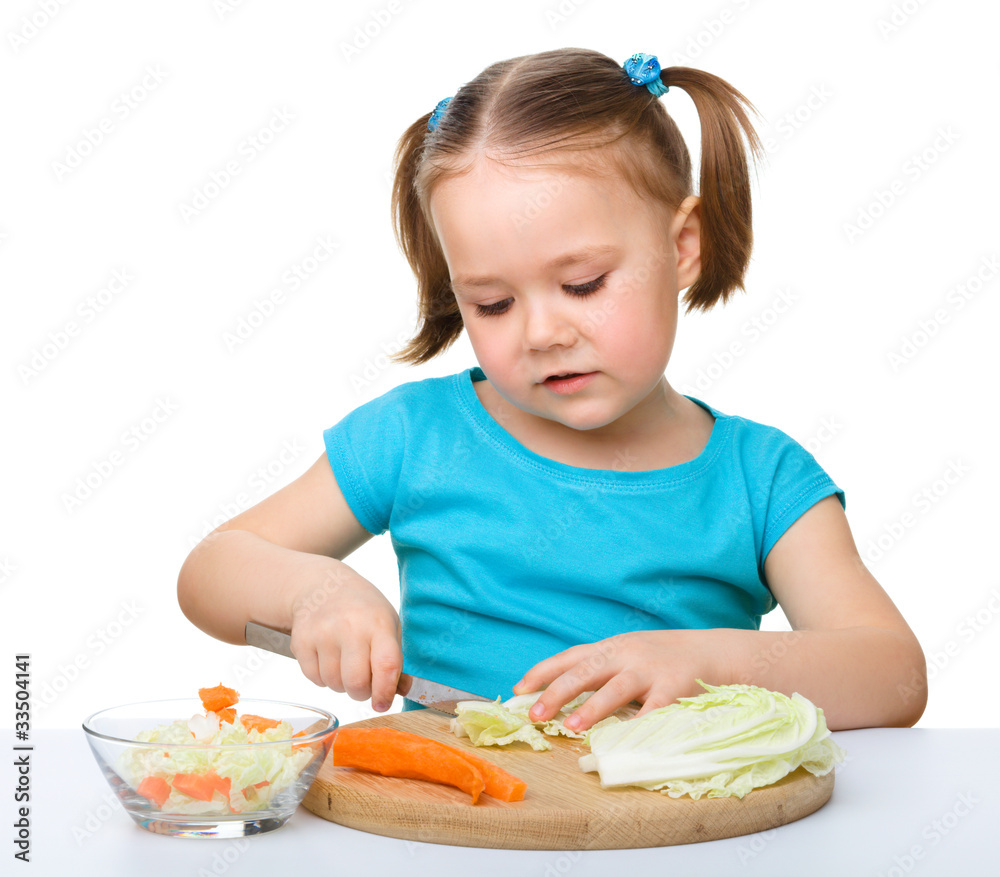 Little girl is cutting carrot for salad Little girl is cutting carrot for salad