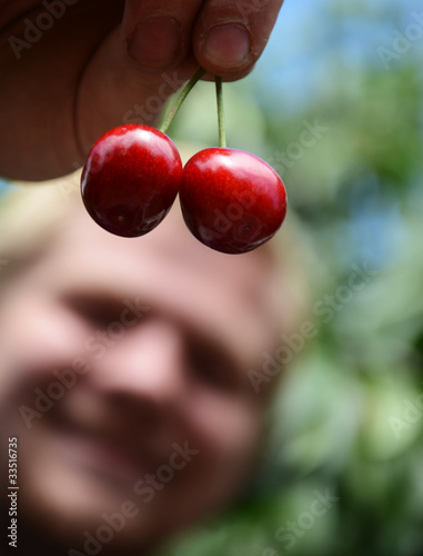 Teen Boy Smiling and Holding Cherries