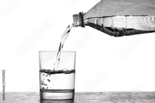 Вода льется из пластиковой бутылки в стеклянный стакан
