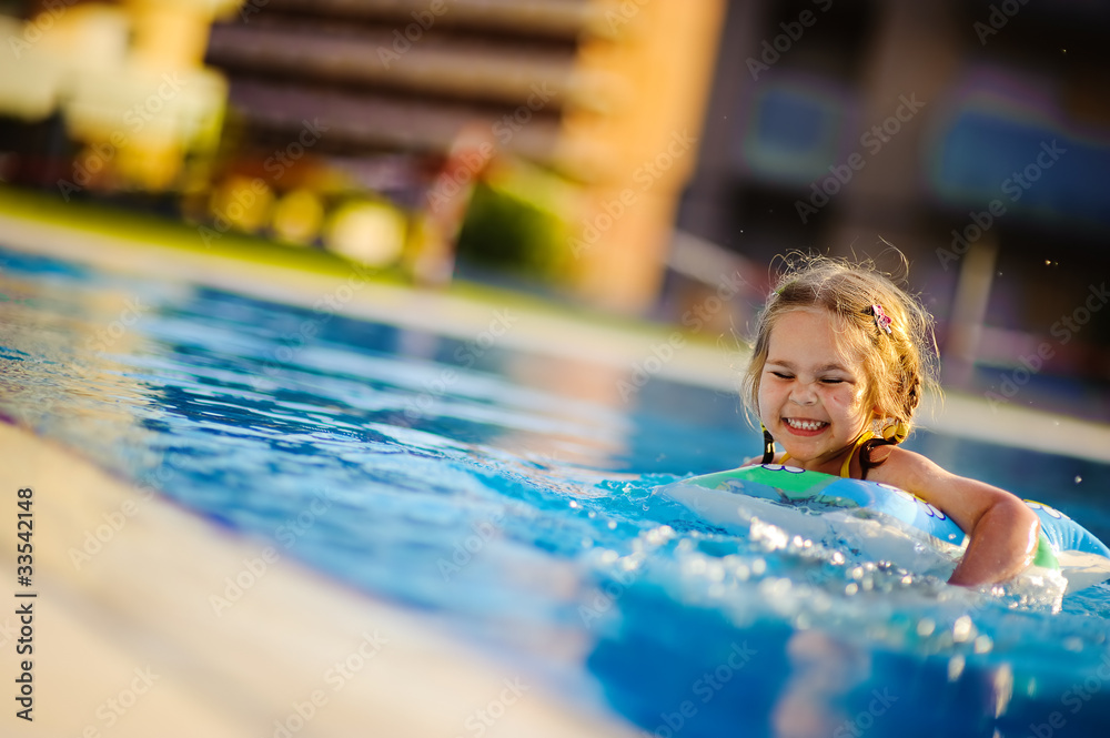 smiling toddler girl swimming in outdoor pool