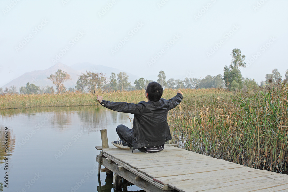 Man resting on a pontoon by a lake Man resting on a pontoon by a lake