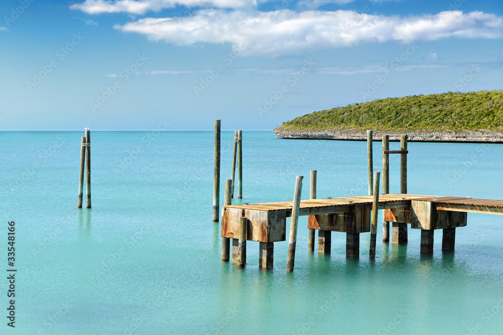 Mooring posts and pontoon leading in turquoise blue sea