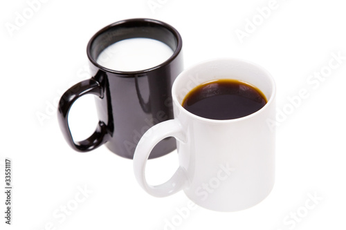 Black cup with milk and a white cup with black coffee.