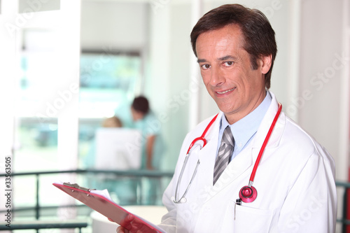 Male doctor holding red clipboard