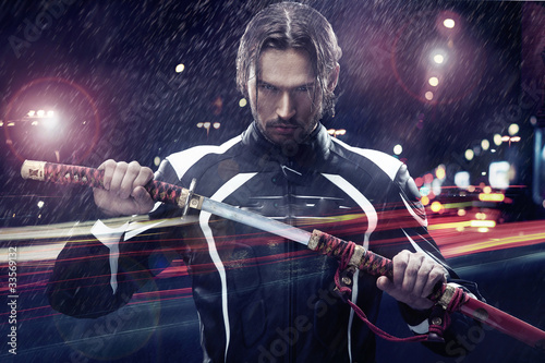 Man holding a samurai sword on a night city street