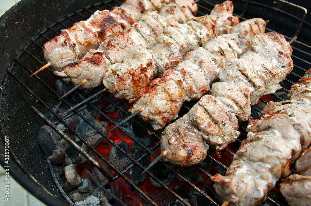 Grilled barbecue sticks cooking on burning coals on mangal outdo