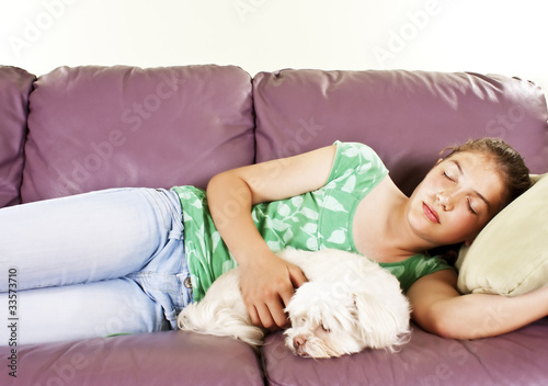 Teenage girl and her dog sleeping together on a sofa