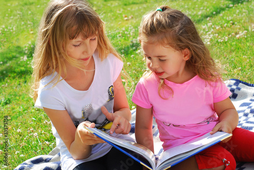 two girls reading a book in the garden