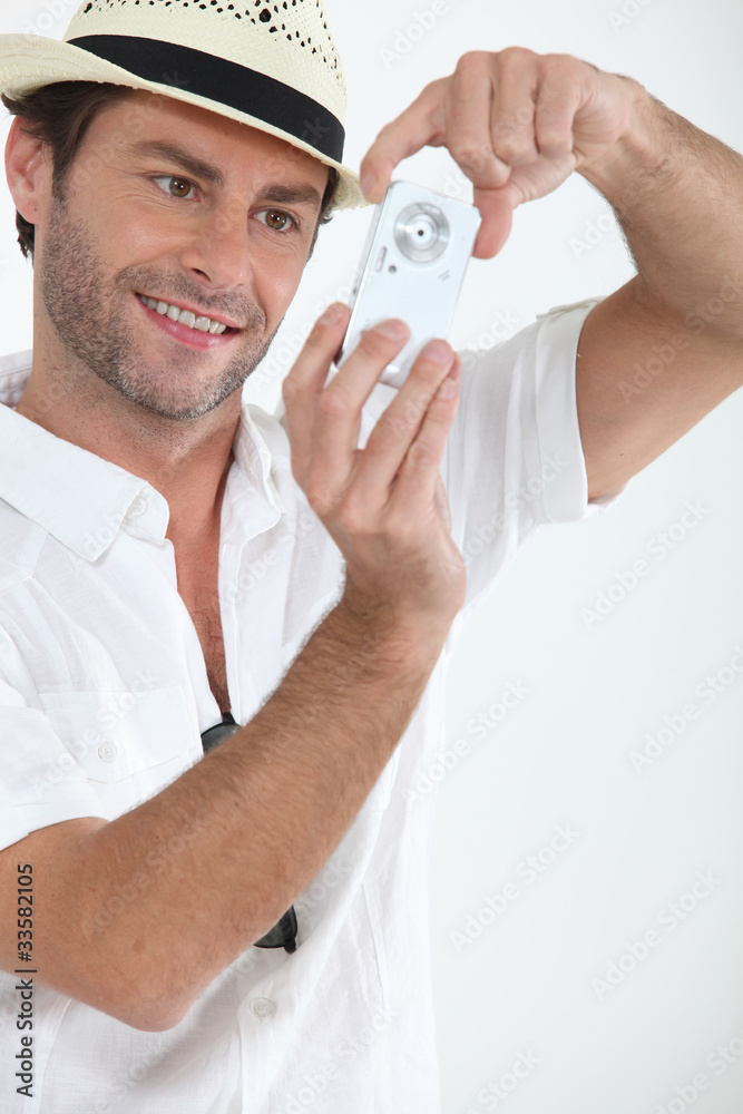 Man wearing straw hat holding digital camera Man wearing straw hat holding digital camera