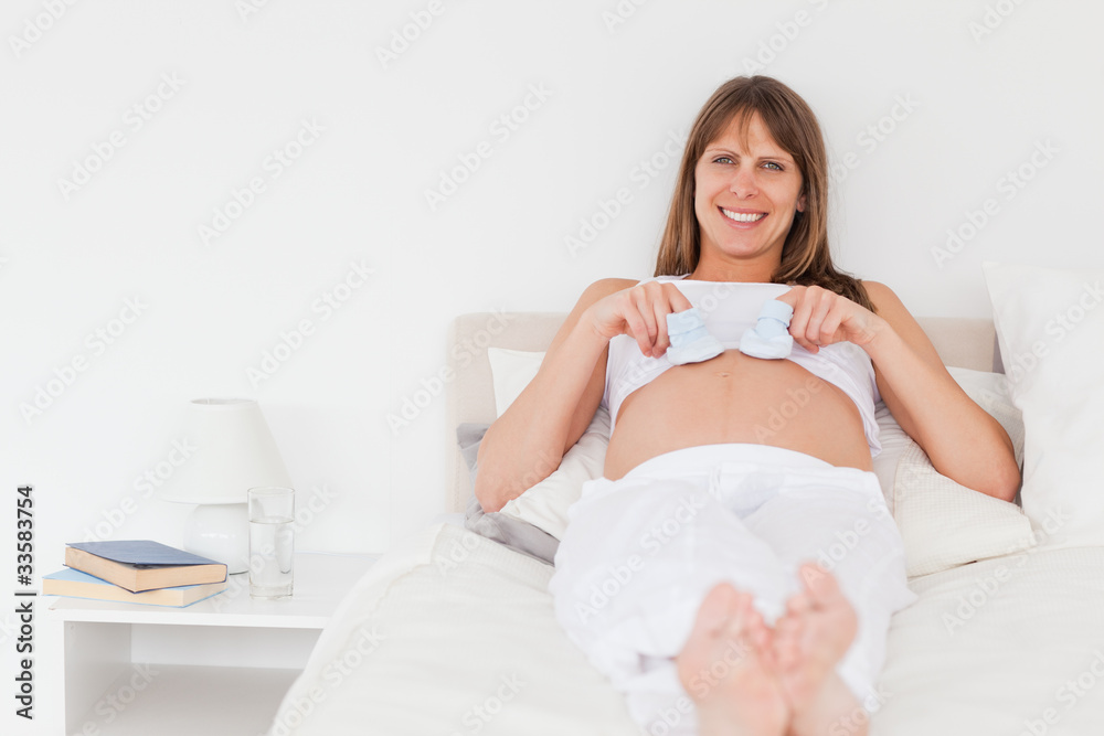 Charming pregnant female playing with little socks while lying o Charming pregnant female playing with little socks while lying o