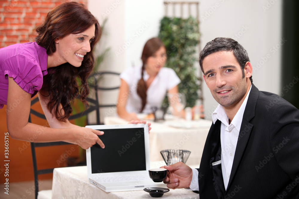 Woman in a restaurant pointing to a computer Woman in a restaurant pointing to a computer