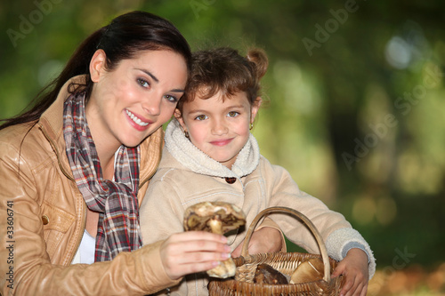 Young woman and little girl picking mushrooms in the countryside
