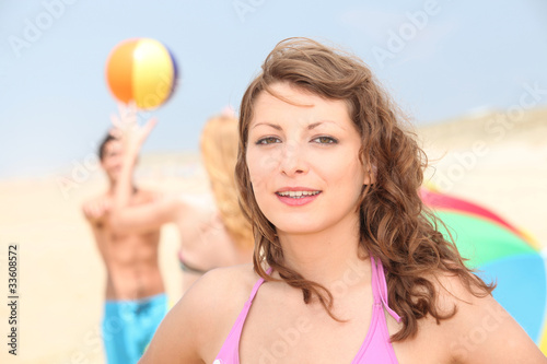 Teenage girl at the beach with two friends in the background