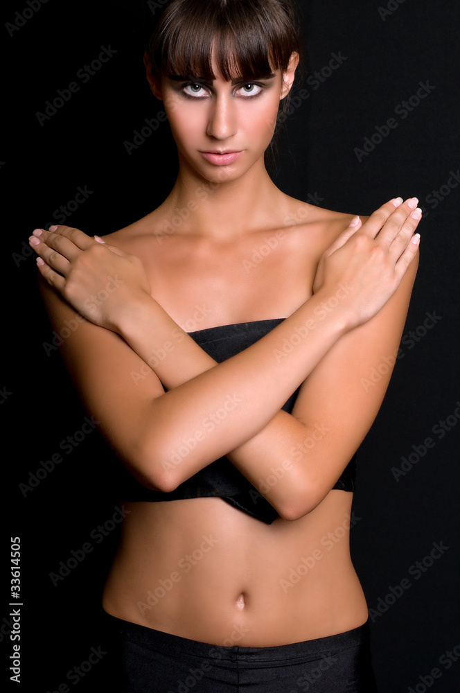 Fototapeta premium beautiful brunette with crossed hands on a breast on black