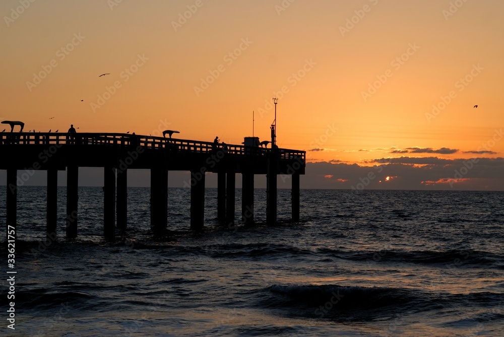 fishermen silhouetted on fishing pier at sunrise florida