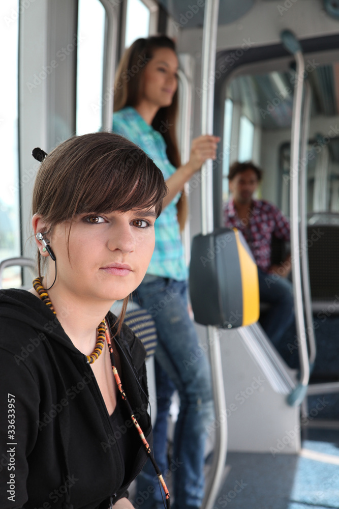 Photo of teenager riding the tram with passenger in background Photo of teenager riding the tram with passenger in background