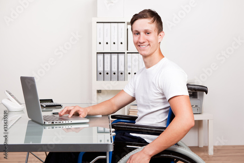junger mann im rollstuhl am arbeitsplatz photo