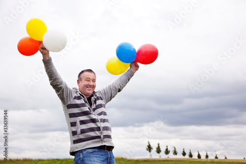 Mann mit Luftballons freut sich 588