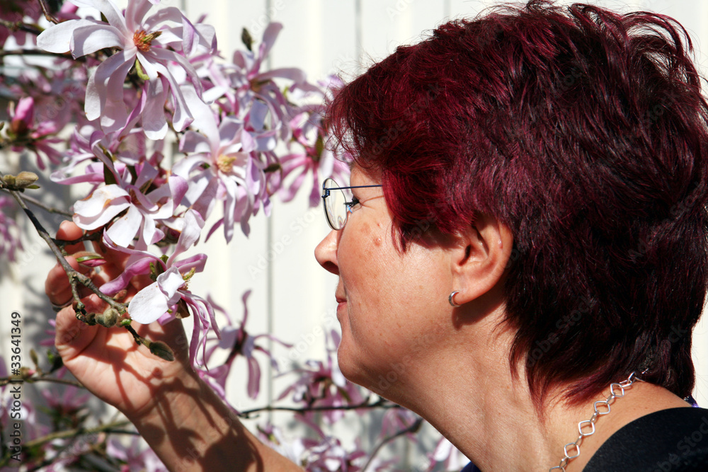 Fototapeta premium Frau riecht an einer Magnolienblüte