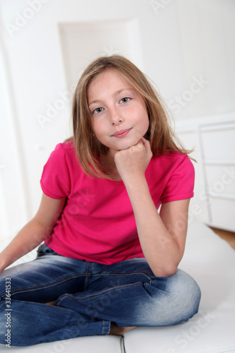 Portrait of blond girl with cross-legged on sofa