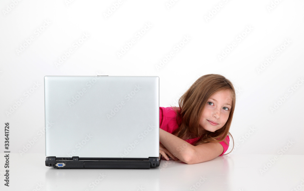 Portrait of blond little girl behind laptop computer Portrait of blond little girl behind laptop computer