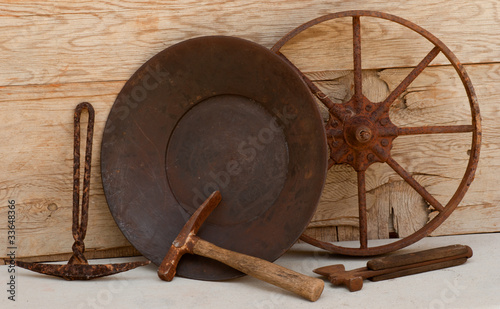 Old mining tools, gold pan, picks against wood background
