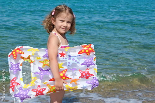 little girl with airbed standing in the sea