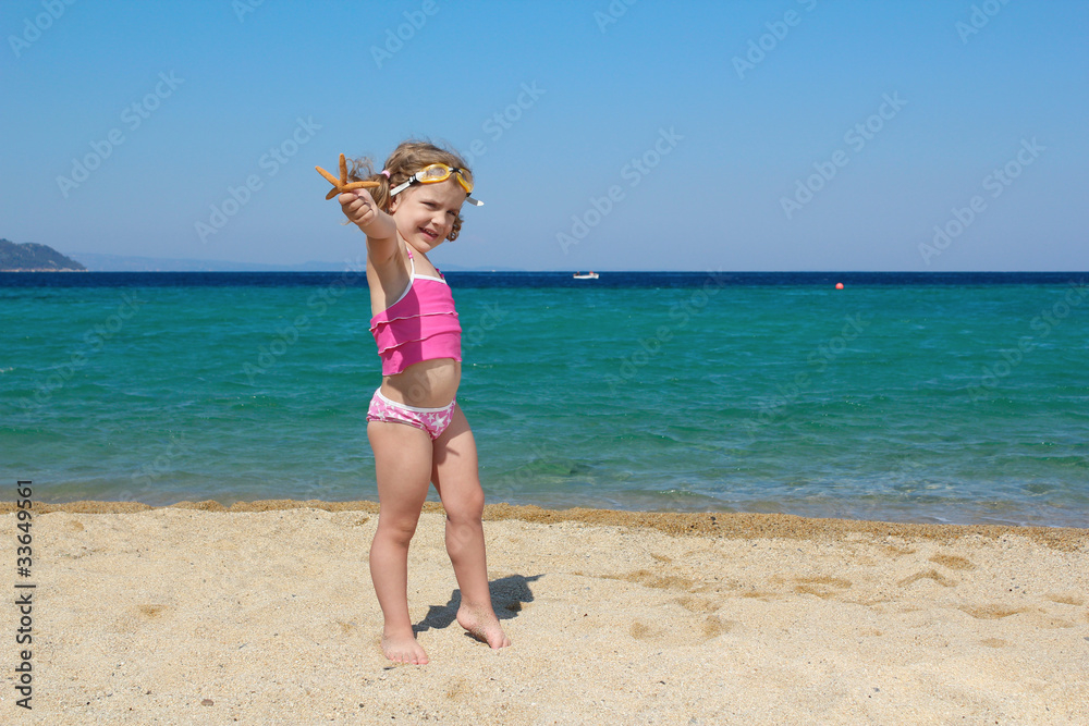 little girl with starfish and goggles on beach little girl with starfish and goggles on beach