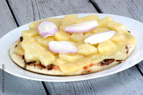 Pizza mit Käse und Ananas auf einem weißen Teller