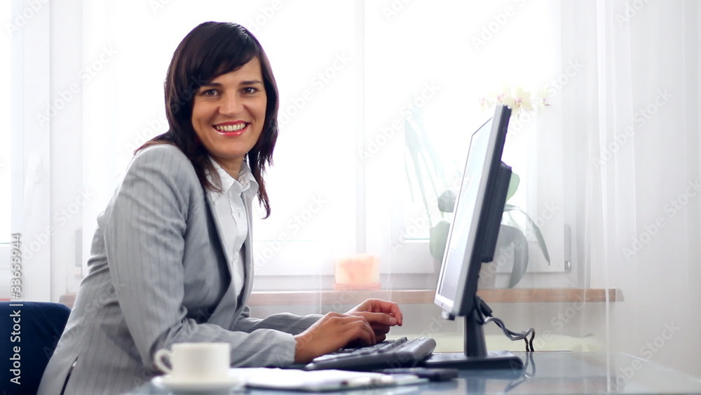 Businesswoman working on computer and smiling Businesswoman working on computer and smiling