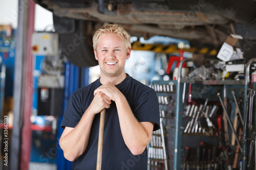 Smiling mechanic holding broom photo