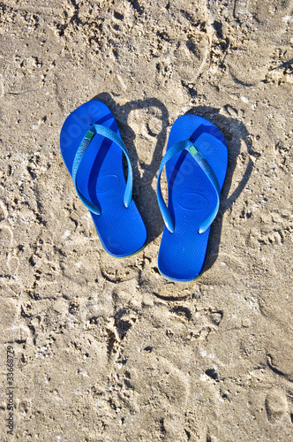 Blue summer shoes on the beach. Flip-flops on the sand.