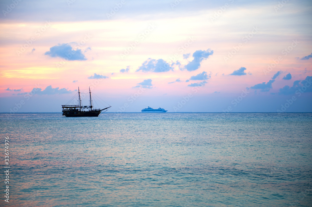 Boat in a landscape of sunset colors over the ocean.