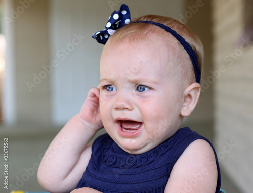 baby girl holding her ear in pain