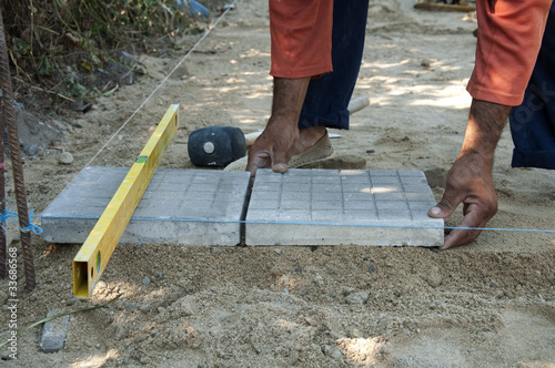 Worker puts sidewalk tiles photo