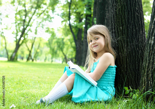 Portrait of little girl reading a book in the park © Sergey Nivens