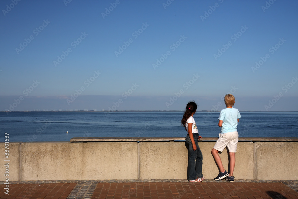 Mädchen und Junge blicken auf das Meer