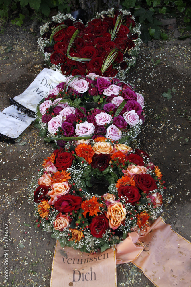 Fototapeta premium Blumen und Kränze auf einem frischen Grab