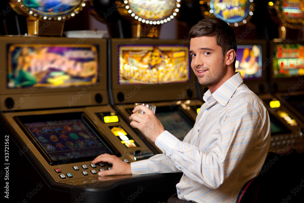 young handsome man next to slot machine