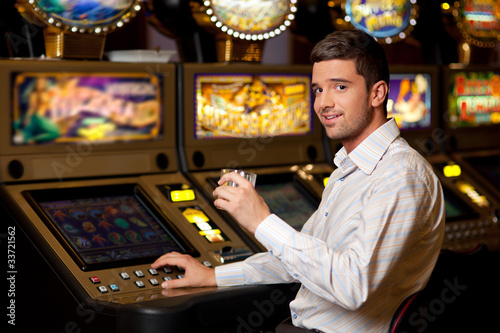 young handsome man next to slot machine