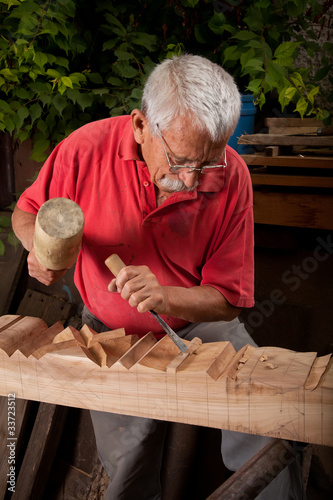 Fototapeta woodcarver working with mallet and chisel
