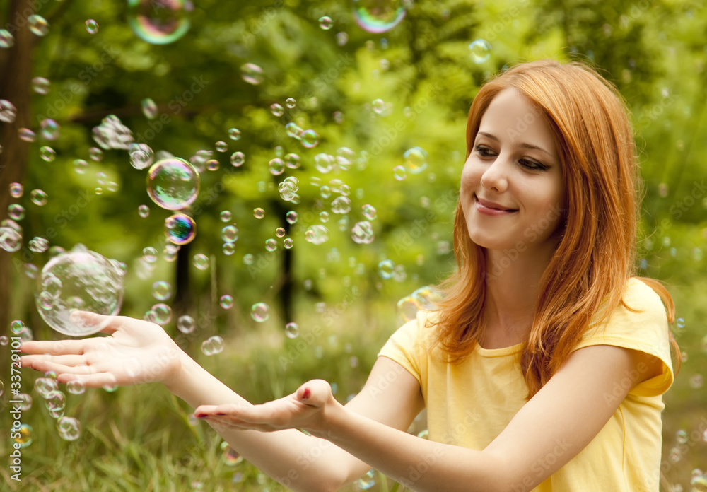Redhead girl in the park under soap bubble rain. Redhead girl in the park under soap bubble rain.