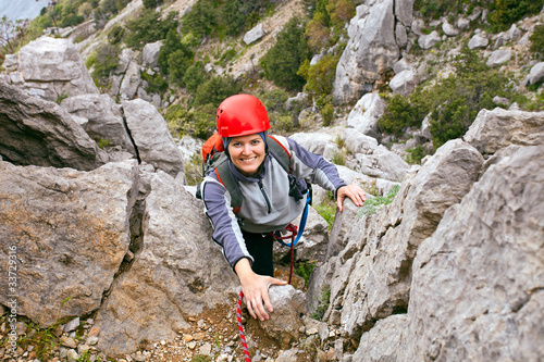 Portrait of cheerful female climber ascending a rock