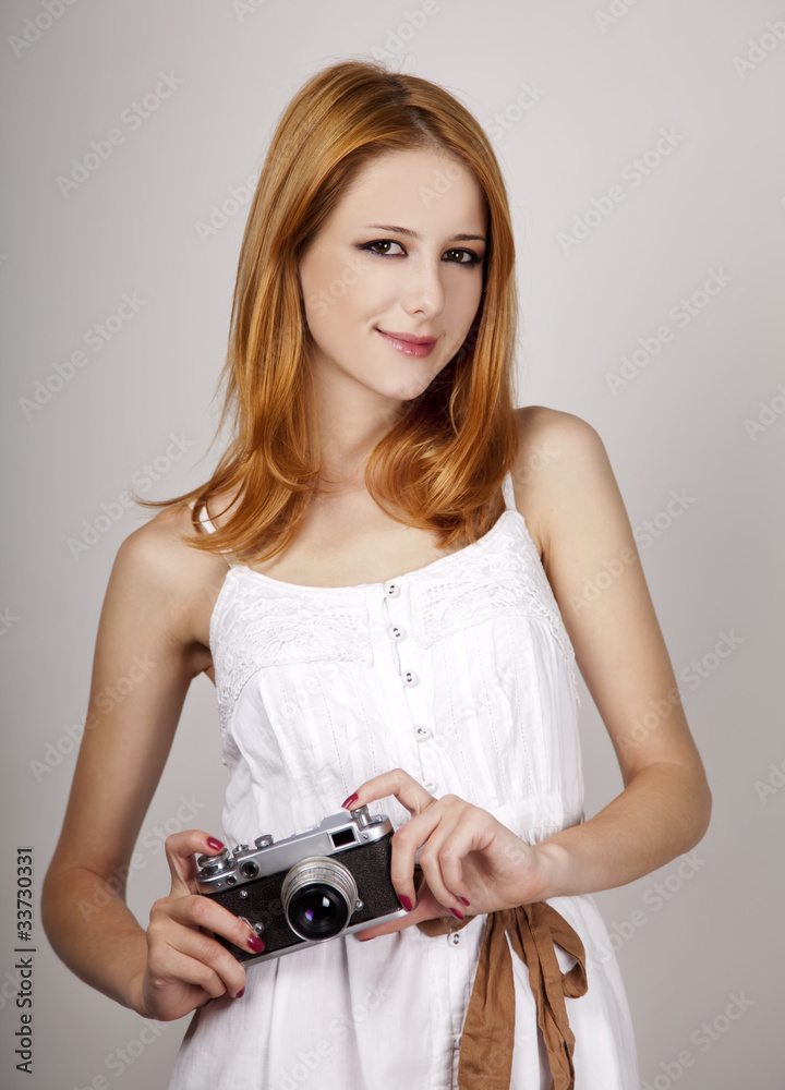 Redhead girl in white dress with vintage camera.