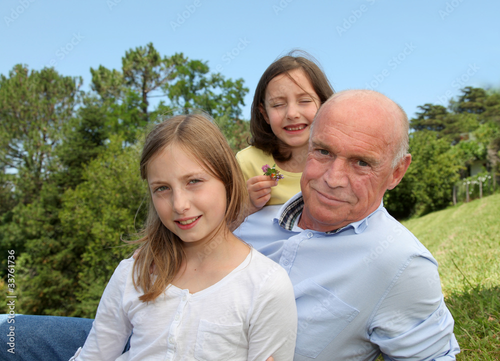 Grandfather with grandkids sitting in park Grandfather with grandkids sitting in park