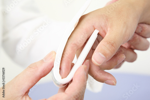 指の骨折をシーネで固定する医者の手元